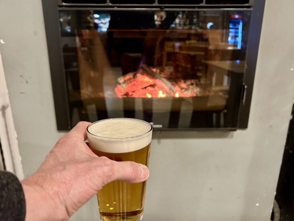 Ein Glas kühles Bier vor dem Kamin